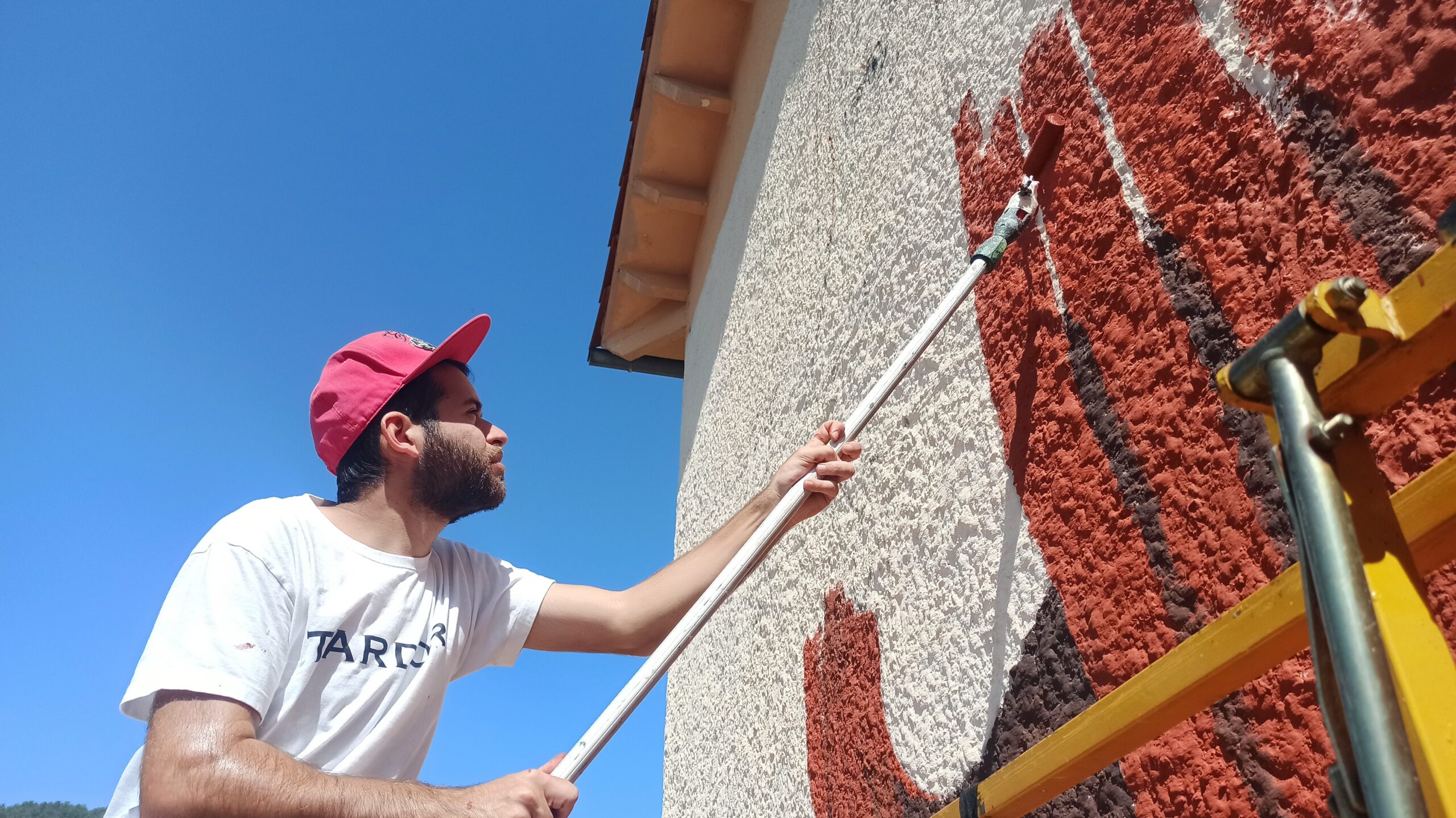 Mural urbano en Campdevànol desde perspectiva amplia — obra mural de Tardor.
